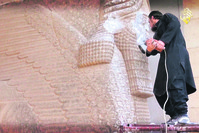 A militant attempts to damage the ancient statue.