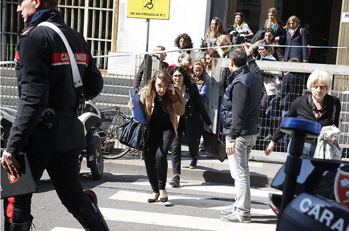 A plainclothes policeman helps to evacuate people from the tribunal building in Milan, Italy, after a shooting was reported inside a courtroom Thursday, April 9, 2015 AP Photo