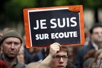 A protester holds up a placard which reads ,I know they tap my phones , as he demonstrates against the surveillance bill a day ahead of its vote in parliament in Paris May 4, 2015 (Reuters Photo)