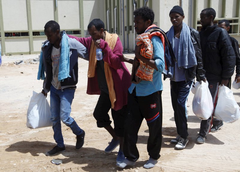 Migrants help another migrant walk to a bus bound for an immigration centre in the coastal city of Misrata, Libya, May 9, 2015 (Reuters Photo)