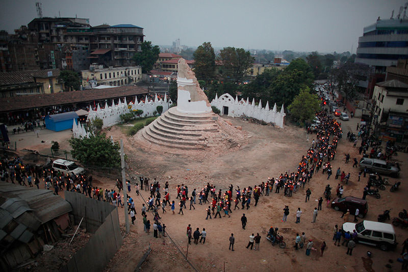 In this Thursday, May 7, 2015, file photo, Nepalese people pay tribute to the victims of the April 25 earthquake, as they walk with lighted candles past the destroyed Dharahara tower in Kathmandu, Nepal (AP Photo)