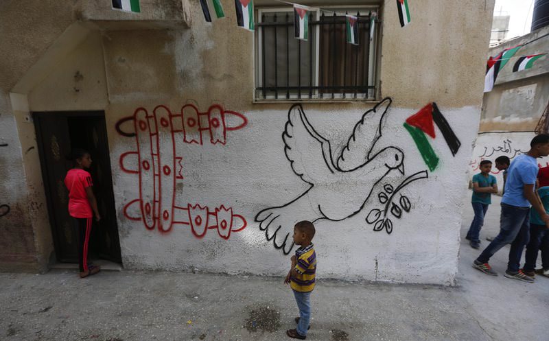 Palestinian children play close to a mural at the Al-Amarrie refugee camp near Ramallah (EPA Photo)