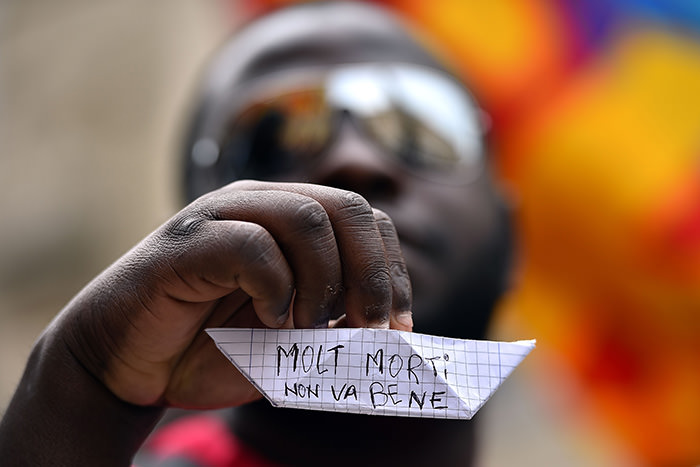 An asylum seekers holds a paper boat, with words written in Italian that read, ,Too many deaths, it is not good, during a demonstration in front of the Italian parliament in Rome, on April 23, 2015 (AFP Photo)