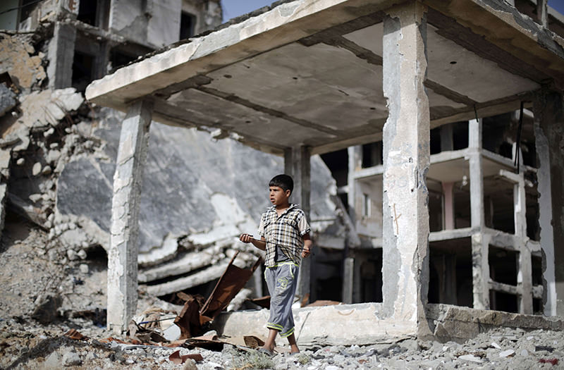A Palestinian boy walks on May 27 2015 in front of buildings that were destroyed during the 50-day war in the summer of 2014, in the Gaza Strip town of Beit Hanun (AFP Photo)
