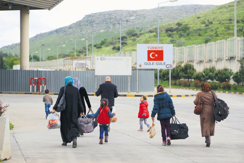 Syrians walking toward the Cilvegu00f6zu00fc border crossing to enter Syria against the backdrop of a sign reading ,goodbye, in Turkish.
