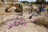 A small memorial reading in Arabic, , the martyrs of Speicher, is seen as members of the Iraqi security forces inspect a mass grave containing the remains of people in the city of Tikrit, on April 12, 2015 (AFP Photo)