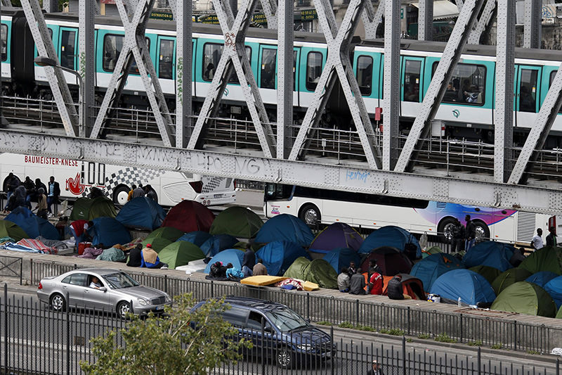An elevated metro passes over a bridge which provides shelter for migrants who have established a make-shift tent city in Paris France, May 29, 2015 (Reuters Photo)