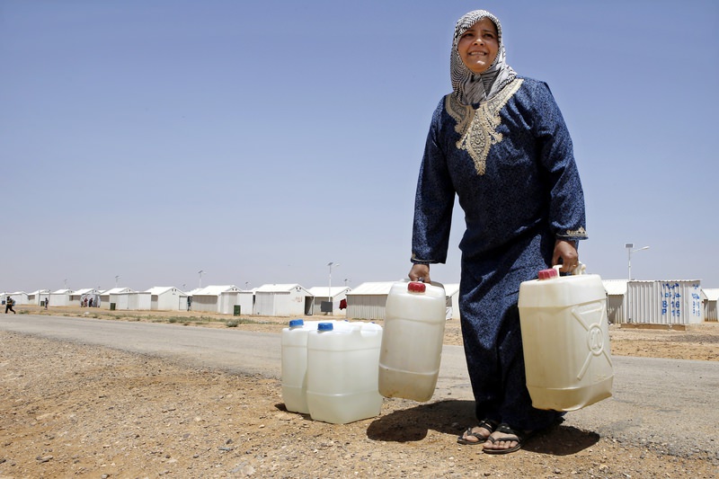  Syrian refugee Siham Hamish, 43, carries water containers at Azraq refugee camp, Jordan. (AP Photo)
