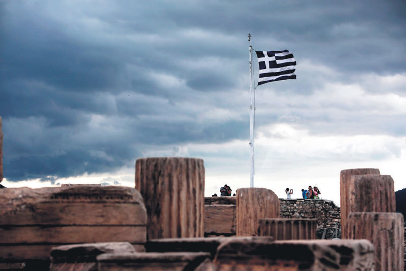 A Greek flag waves in the breeze at the Acropolis in Athens on Friday. Greece bought time in debt crisis negotiations with official creditors when it moved to bundle four looming IMF loan payments into one to be paid by the end of June. 