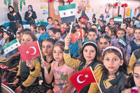 Young Syrian students at a school for refugees waving Turkish and Syrian flags at an event on June 1 in the southern city of Hatay.