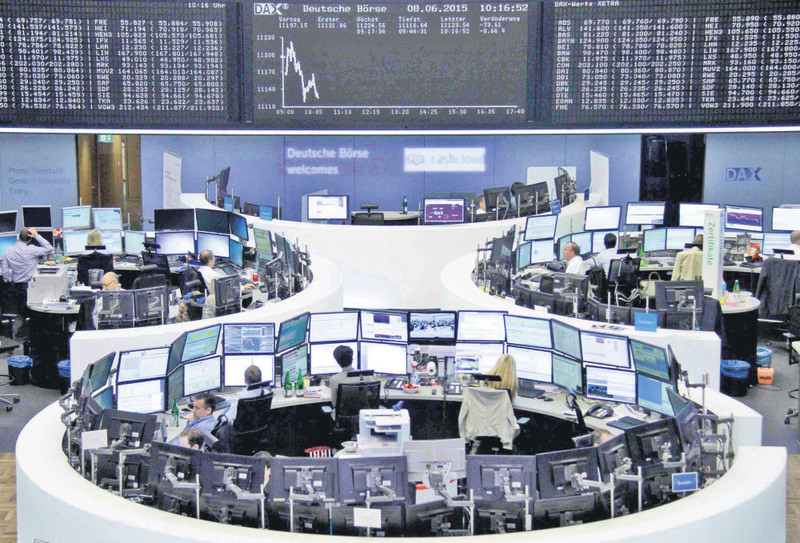 Traders work at their screens in front of the German share price index DAX board at the stock exchange in Frankfurt.