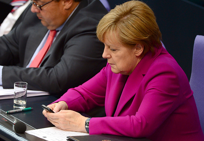  German Chancellor Angela Merkel (R) reading her mobile phone during a session of the Bundestag Lower House of parliament in Berlin (AFP Photo)