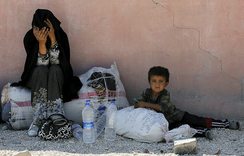 Syrian refugee woman from the northern Syrian town of Tel Abyad and her child wait while spending the day in Aku00e7akale, in u015eanlu0131urfa province, Turkey, June 18, 2015 (REUTERS Photo)