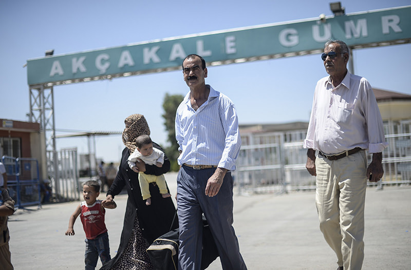 Syrian refugees walk along the road that leads to the Aku00e7akale border gate as they wait to return to their home in the northern Syrian town of Tel Abyad, in u015eanlu0131urfa province, on June 18, 2015 (AFP Photo)