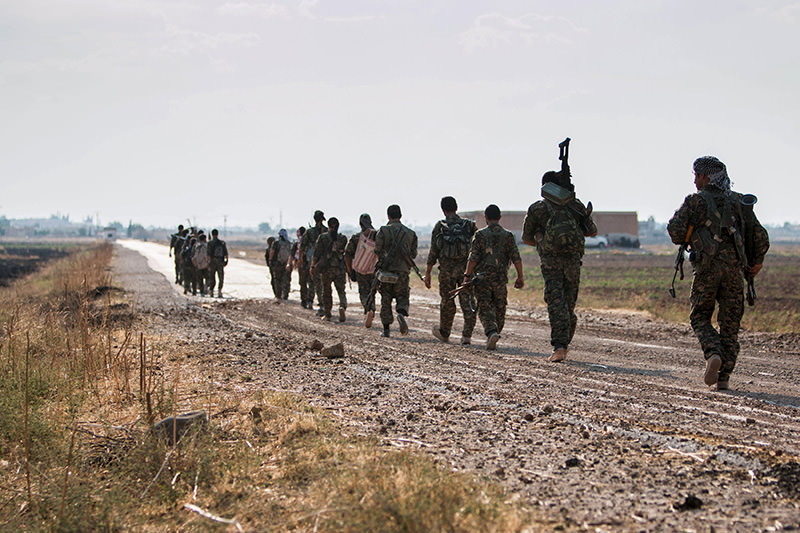 Syrian Kurdish YPG militia fighters walk carrying their weapons towards Tel Abyad of Raqqa governorate after they said they took control of the area from ISIS on June 15, 2015 (Reuters Photo)