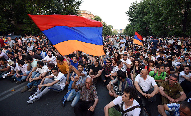 Demonstrators wave their national flags as they sit during a protest against the increase of electricity prices in Yerevan, the capital of Armenia, on June 22, 2015. (AFP Photo)