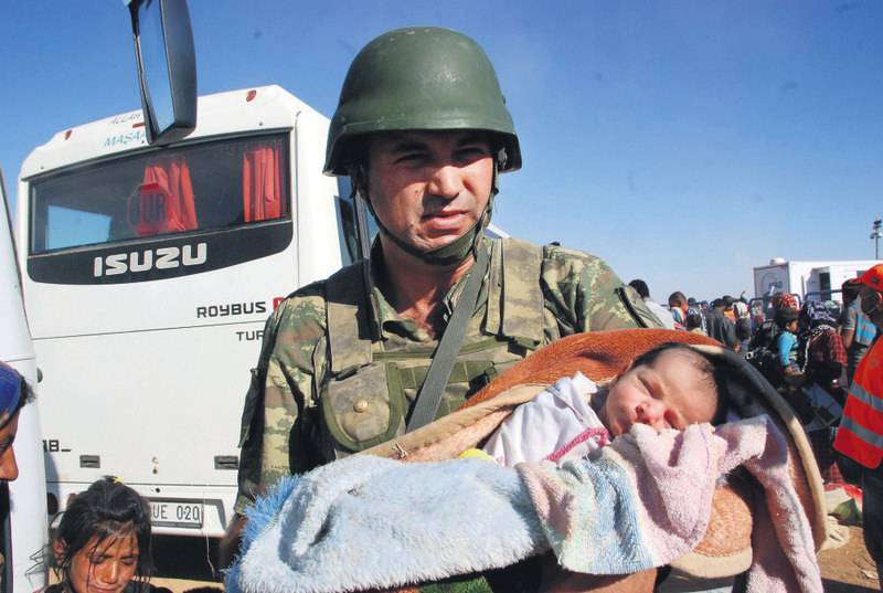 Ferman, cradled by a Turkish soldier on the border, was born in a Turkish border town her mother took shelter in minutes after the Syrian family which fled Kobani in Syria, arrived there last year.