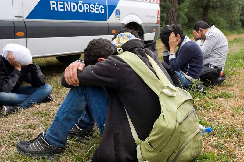 Migrants who were captured on a small island in the Tisza River next to a police van near Serbian border.