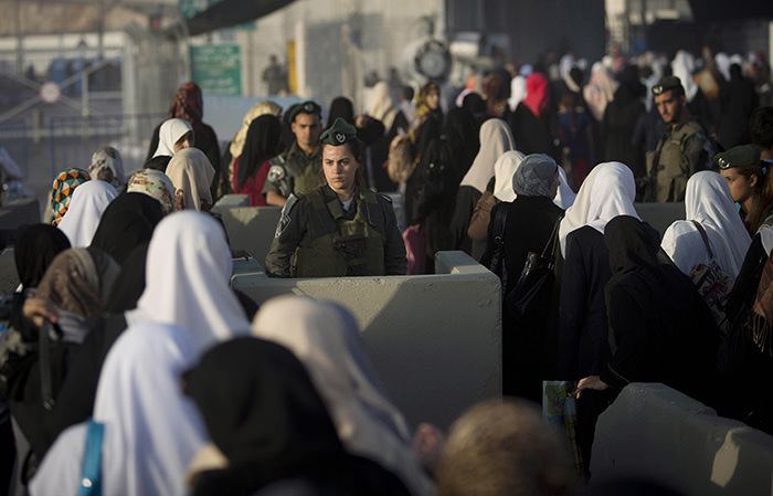 Palestinian women walk past an Israeli border police officer on their way to pray at the Al-Aqsa Mosque in Jerusalem (AP Photo)