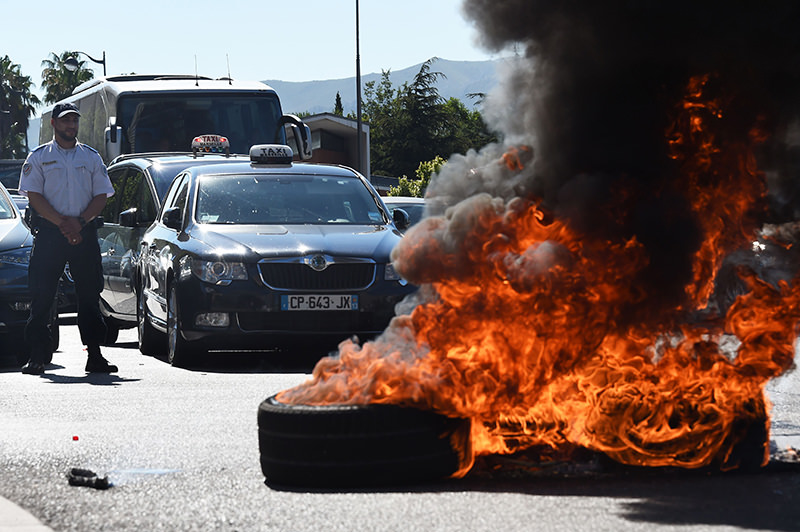 French Taxi drivers burn tires as they protest in the southern city of Marseille on June 25, 2015 as they demonstrate against UberPOP, a popular taxi app that is facing fierce opposition from traditional cabs. (AFP Photo)