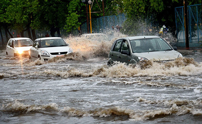 Indian commuters make their way through a water logged street during heavy rain in Bhopal, India, 22 June 2015 (EPA Photo)