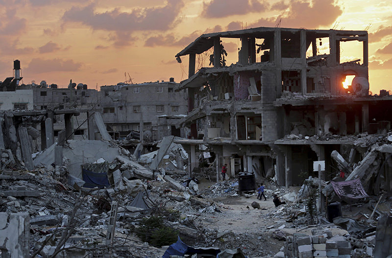 Palestinians walk during the sunset between the rubble of their destroyed building in Shijaiyah neighborhood of Gaza City in the Northern Gaza Strip, Oct. 12, 2014 (AP Photo)