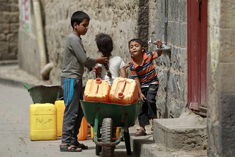 Yemeni children carry jerrycans to fill them with water from a public tap amid an acute shortage of water supply to houses during the fasting month of Ramadan in the capital Sanaa, on June 21, 2015 (AFP PHOTO)