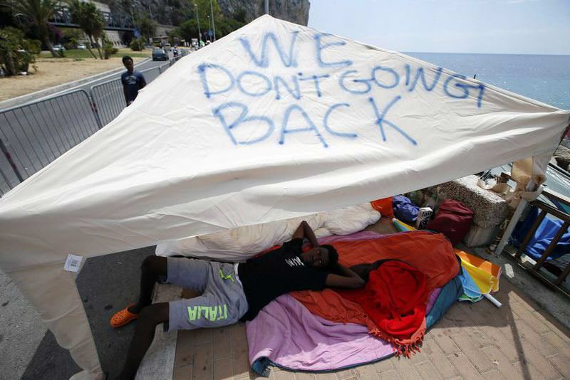 A migrant lies in the shade of a tent with the words ,We don't going back, written on it in the Italian city of Ventimiglia on the Italian-French border.