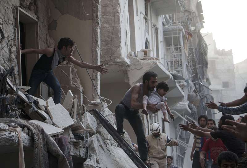 A man evacuates a child from a building following a barrel bomb attack by Syrian regime forces on the northern Syrian city of Aleppo, on May 30, 2015 (AFP Photo)