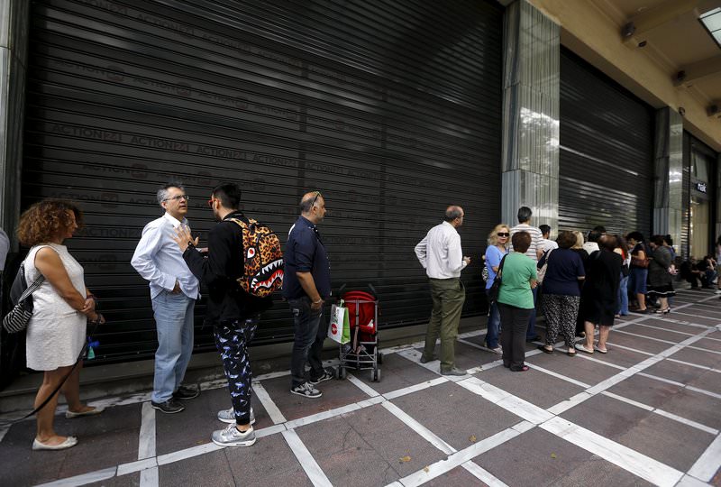 People wait outside a closed branch of Piraeus Bank in Athens, Greece June 27, 2015 (Reuters Photo)