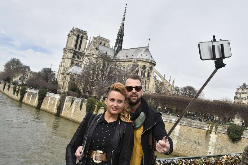 photo shows tourists as they use a selfie-stick to take a picture of themselves near the Notre Dame cathedral in Paris. (AFP Photo)