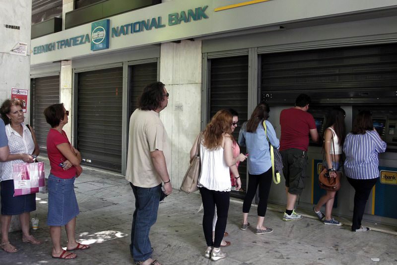 People wait in a queue to withdraw money from an ATM outside a branch of Greece's National Bank in Athens yesterday. Greek PM Tsipras called for a referendum on the Greek debt deal on July 5.