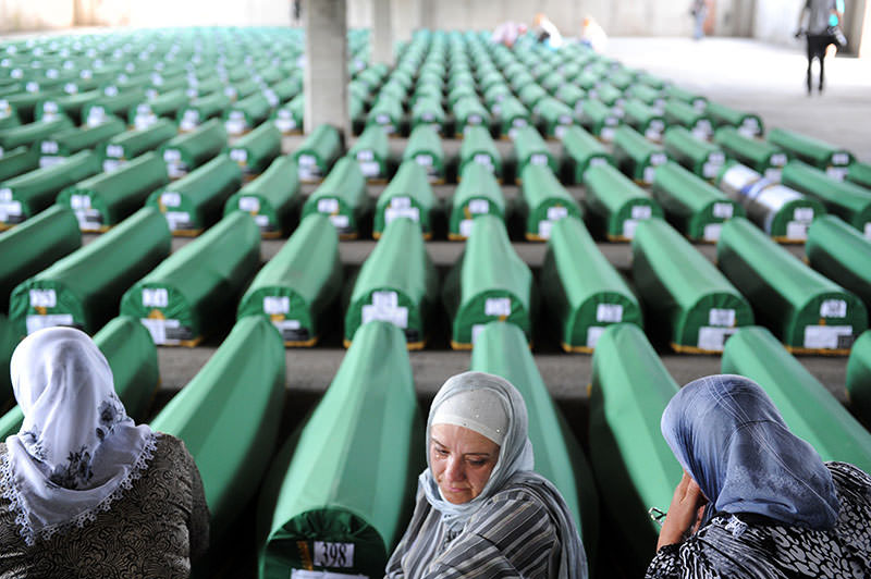 Bosnian Muslim women cry and pray among 520 caskets stocked in an abandoned factory hangar, in preparation for a mass burial ceremony at the Srebrenica Memorial Cemetery, in Potocari on July 10, 2012 (AFP Photo) 