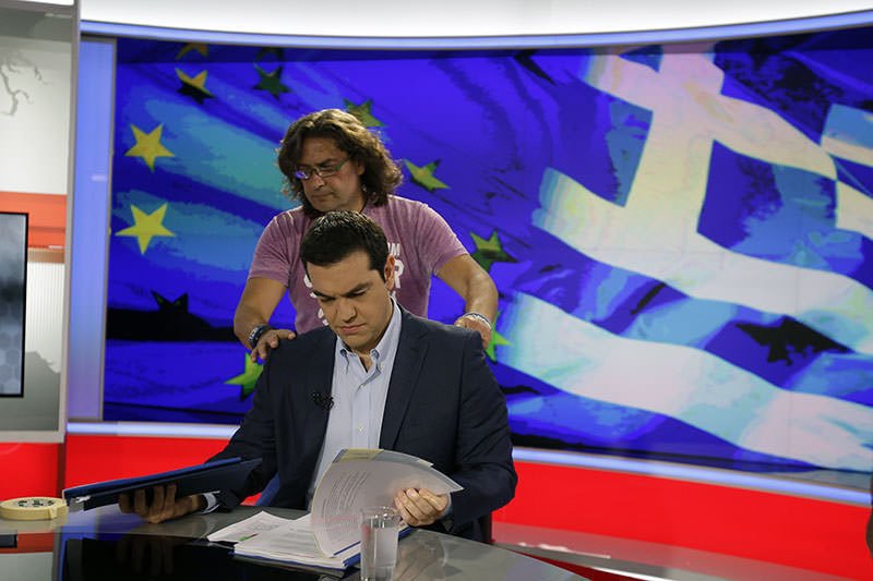 Greece's Prime Minister Alexis Tsipras takes a look at his notes as a technician prepares him before a TV interview at the State Television (ERT) in Athens, Monday, June 29, 2015 (AFP Photo)