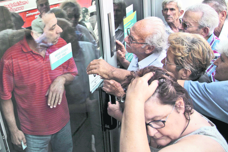 Pensioners waiting outside a closed National Bank branch and hoping to get their pensions, argue with a bankemployee (L) in Iraklio on the island of Crete.