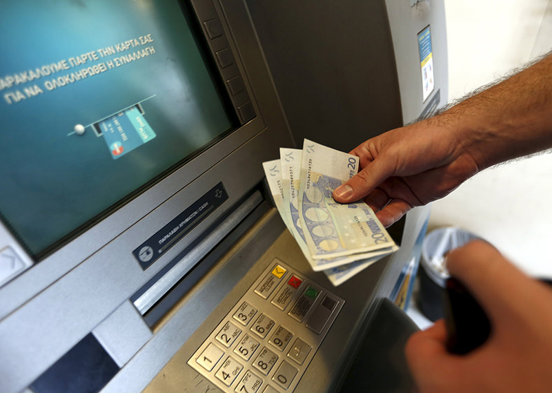 A man withdraws sixty Euros, the maximum amount allowed after the imposed capital controls in Greek banks, at a National Bank of Greece ATM in Piraeus port near Athens, Greece June 30, 2015 (Reuters Photo)