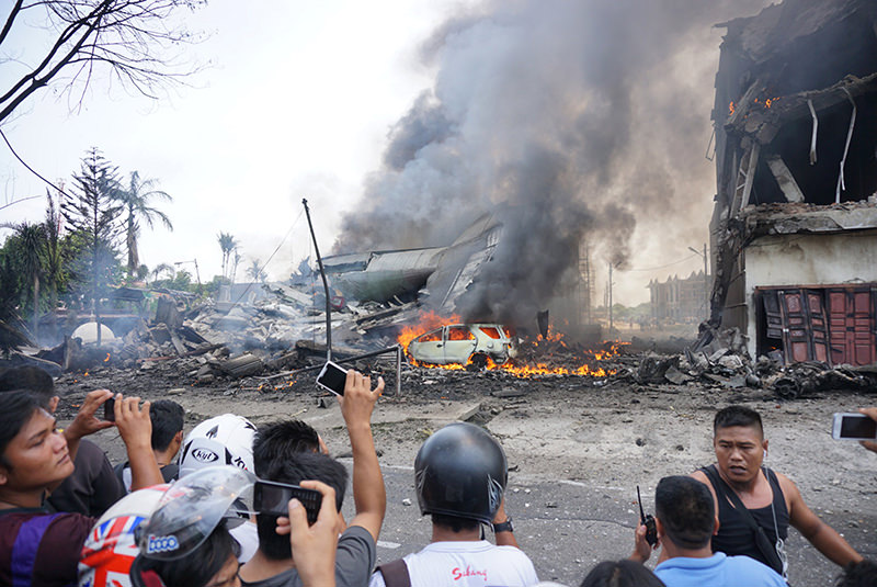 People look at a military plan crash in Medan on June 30, 2015. An Indonesian military transport plane crashed on June 30 shortly after taking off and exploded in a ball of flames in a residential area. (AFP Photo)