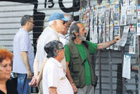 People read the morning newspapers on a kiosk in central Athens on Friday. Prime Minister Alexis Tsipras and Minister of Finance Euclid Tsakalotos briefed in detail the Syriza parliamentary group on the latest developments early the same morning.