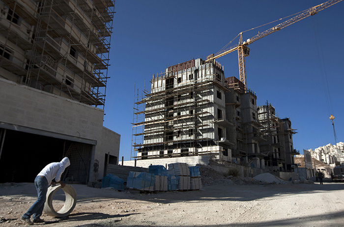 a construction worker works at a site of a new housing unit in the east Jerusalem neighborhood of Har Homa (AP Photo)