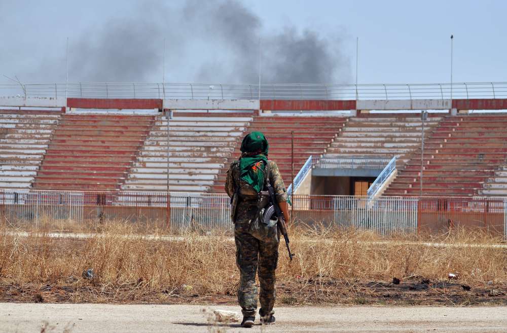 A member of the Kurdish People's Protection Units (YPG) walks in the damaged stadium in the Al-Nashwa neighborhood of the northeastern Syrian province of Hasakeh.       