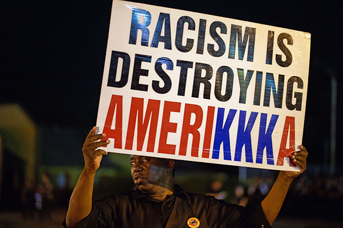 A man holds a sign during a civil disobedience action on West Florissant Avenue in Ferguson, Missouri on August 10, 2015