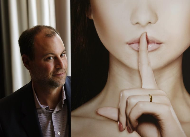 Ashley Madison founder Noel Biderman poses with a poster during an interview at a hotel in Hong Kong.