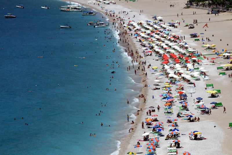 Holidaymakers enjoy the sea and fine weather in an aerial view of a Southern Aegean coast.