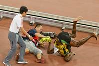 Usain Bolt (R) falls after being knocked over by a cameraman (C)  as he celebrates his 200 metres win during the 15th IAAF World Championships, August 27, 2015. (REUTERS Photo)