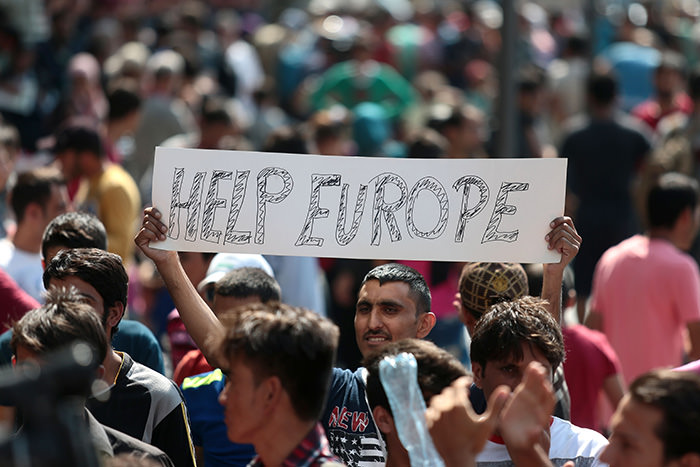 Man holds a placard reading ,Help Europe, as Syrian and Afghan refugees attend a protest to demand to travel to Germany on September 2, 2015 in Budapest (AFP Photo)