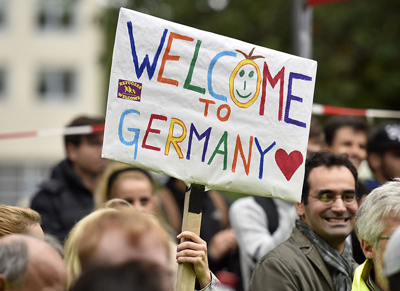 People welcome refugees with a banner reading 'welcome to Germany' in Dortmund, Germany, Sunday, Sept. 6, 2015, where thousands of migrants and refugees arrived by trains. (AP Photo) 