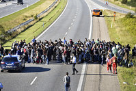 A group of refugees and migrants who were walking north stand on the highway in southern Denmark on Wednesday (AP Photo)