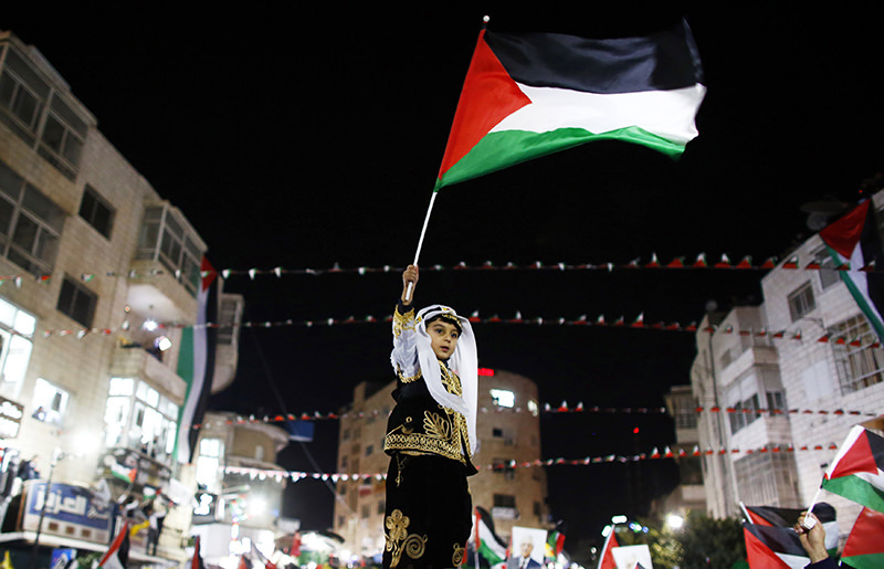 A Palestinian boy in traditional clothes waves a Palestinian flag during a rally in the West Bank city of Ramallah November 29, 2012 (Reuters Photo)