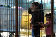 Children wait behind a fence to pass with their families in the southern Macedonian town of Gevgelija, Friday, Sept. 11, 2015 (AP Photo)