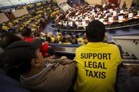 Uber protesters in yellow shirts listen to the Toronto city council debate over new taxi regulations.